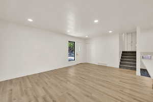 Unfurnished living room with light wood-style flooring, stairs, and recessed lighting