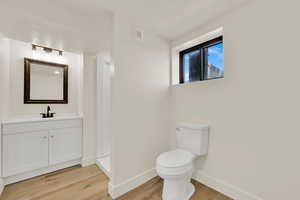 Bathroom with wood finished floors, vanity, and a textured ceiling