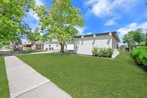 View of side of home with concrete driveway and a lawn