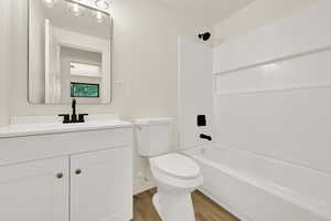 Full bathroom featuring wood finished floors, vanity, and bathing tub / shower combination