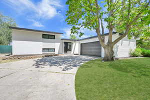 View of front of home featuring driveway, brick siding, a front lawn, and an attached garage