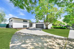 View of front of property featuring driveway, a front yard, brick siding, and an attached garage