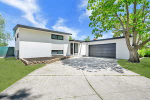 View of front of house with brick siding, concrete driveway, a front yard, and a garage
