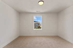 Spare room with light carpet and a textured ceiling