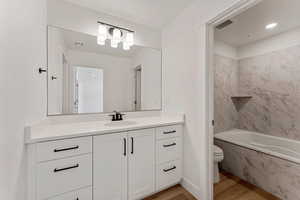 Bathroom featuring wood finished floors, vanity, recessed lighting, and a combined bath / shower with marble appearance
