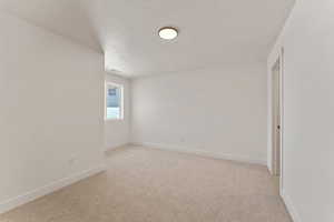 Empty room featuring light carpet and a textured ceiling