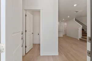 Hallway featuring stairs, recessed lighting, light wood-style floors, and a textured ceiling