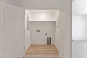 Washroom with hookup for an electric dryer, washer hookup, light wood-style floors, and electric panel