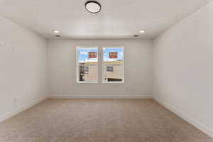 Empty room featuring light carpet, recessed lighting, and a textured ceiling