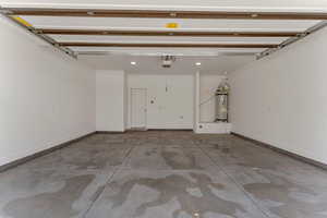 Garage featuring electric water heater and baseboards