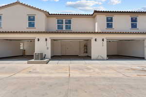 Mediterranean / spanish house with stucco siding, a garage, driveway, and strapped water heater
