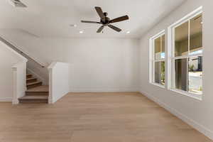 Unfurnished living room with light wood-style flooring, stairway, a textured ceiling, ceiling fan, and recessed lighting