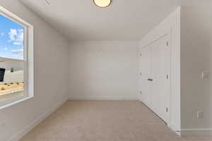 Unfurnished bedroom featuring light colored carpet, a closet, and a textured ceiling