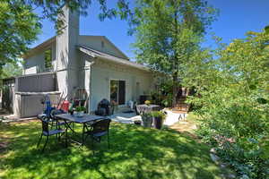 Back of property featuring a yard, a patio, a chimney, and a jacuzzi