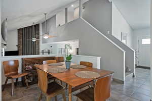 Dining space featuring a textured ceiling, tile patterned floors, stairway, and high vaulted ceiling