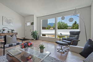 Living area featuring healthy amount of natural light, wood finished floors, vaulted ceiling, and a textured ceiling