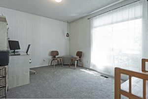 Carpeted office featuring a textured ceiling and baseboards