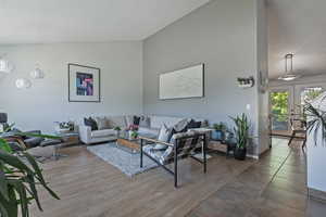 Living area with a textured ceiling, high vaulted ceiling, and wood finished floors