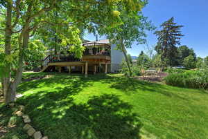 View of green lawn featuring a deck and stairway