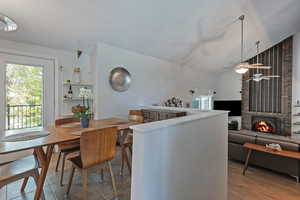 Kitchen featuring a textured ceiling, a brick fireplace, vaulted ceiling, and a ceiling fan