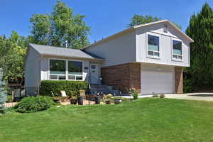 Tri-level home with brick siding, a garage, a front yard, and concrete driveway