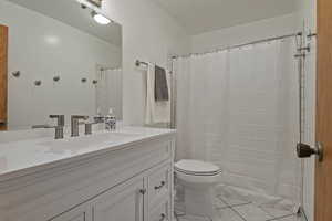 Full bath with vanity, a shower with shower curtain, and tile patterned floors