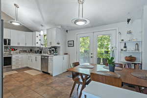 Kitchen with french doors, a textured ceiling, vaulted ceiling, stainless steel appliances, and light countertops