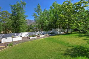 Fenced yard featuring a vegetable garden and a mountain view