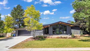 Mid-century modern home with a front lawn, driveway, a garage, and a chimney