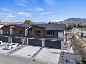 Contemporary home with a mountain view, an attached garage, concrete driveway, and a shingled roof