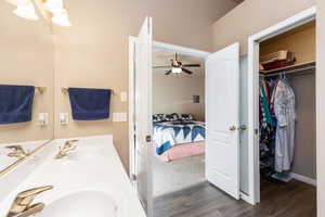 Ensuite bathroom with wood finished floors, double vanity, and a walk in closet