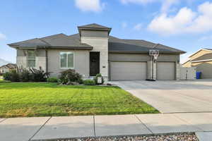 Prairie-style home with roof with shingles, an attached garage, driveway, and stucco siding