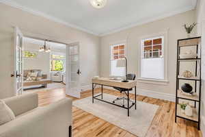 Main floor office space with french doors, crown molding, light wood-style floors, and a chandelier