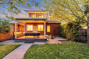 Back of property at dusk with an outdoor hangout area, a wooden deck, and a patio