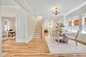 Dining space with an office area, ornamental molding, stairway, light wood-style flooring, and recessed lighting