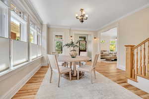 Dining space with a chandelier, stairway, ornamental molding, and light wood finished floors
