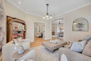 Living room with light wood-style flooring, crown molding, and a chandelier