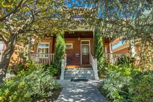 Entrance to property with a porch and brick siding