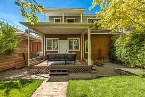 Back of house with an outdoor living space, a deck, and a yard