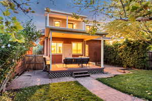 Back of house at dusk with a deck, a gate, and an outdoor hangout area