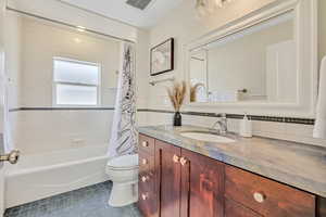 Full bath featuring vanity, tile patterned floors, shower / tub combo with curtain, and tile walls