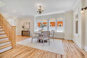 Dining room with stairway, crown molding, light wood finished floors, a chandelier, and recessed lighting