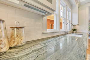 Kitchen view of tasteful backsplash, white cabinets, and light stone counters