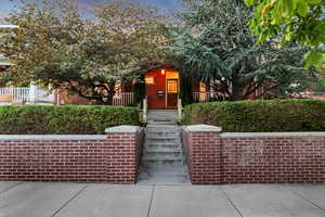 View of front of house featuring brick siding, a porch, and stairway