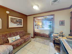 Bedroom with crown molding and light tile patterned flooring