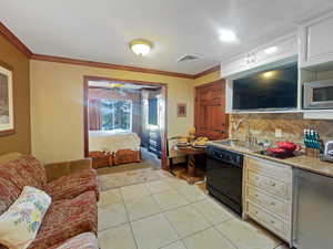 Kitchen featuring crown molding, stainless steel appliances, decorative backsplash, a ceiling fan, and light tile patterned floors