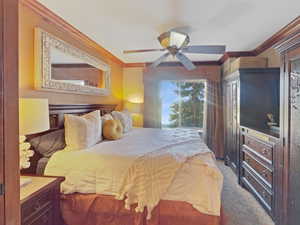 Carpeted bedroom featuring ornamental molding and ceiling fan