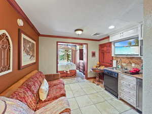 Kitchen with dishwasher, light tile patterned floors, a textured ceiling, ornamental molding, and white cabinets