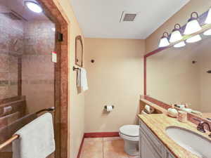 Full bath with vanity, light tile patterned flooring, and tiled shower
