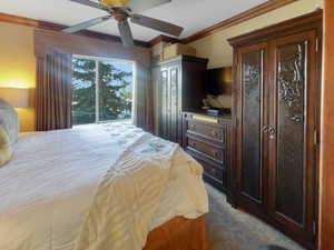 Carpeted bedroom featuring crown molding and ceiling fan